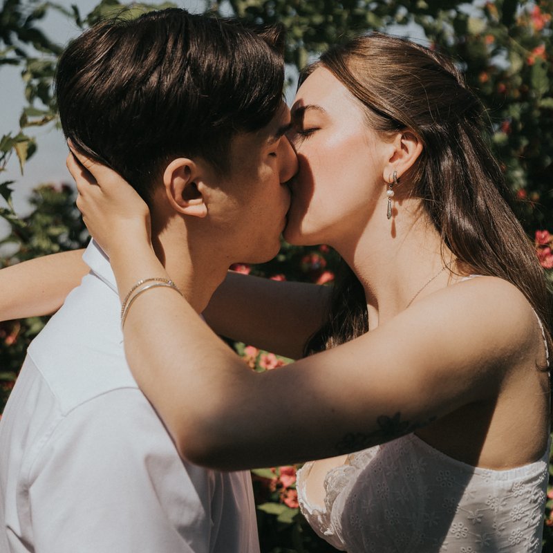 Gabrielle et Cédric s’embrassent devant un buisson en fleurs